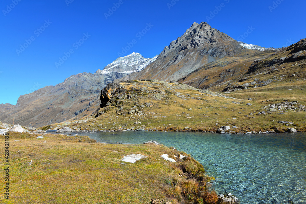 Naklejka premium lake in a valley in alpine national Park in France with mountain peak background