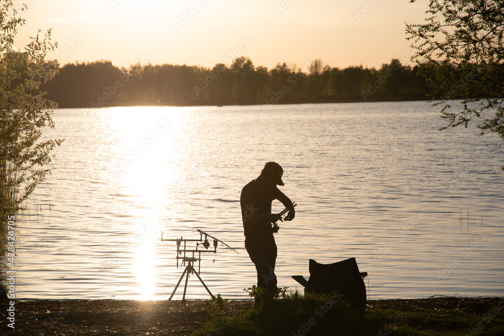 A fisherman silhouette fishing at sunset.
