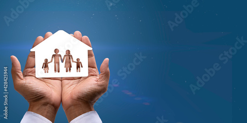 Paper image House of family in cupped hands on black background, for financial, security insurance and Housing loan concept. photo