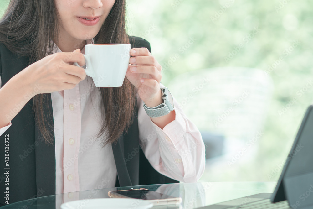 Businesswoman sitting on her workplace in the office, typing, looking at tablet and drinking coffe. Businesswoman sitting on her workplace in the office, typing, looking at tablet and drinking coffe.