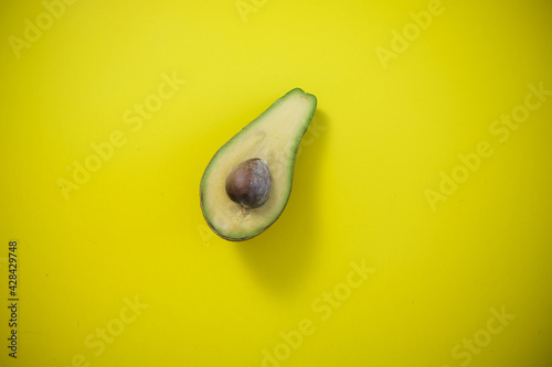Food background with fresh organic avocado on yellow background. the view from the top, One half of