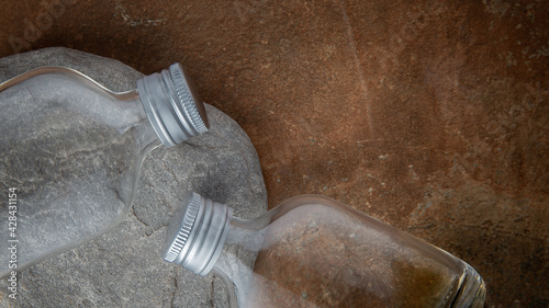 Empty glass bottles on stone background. Glass empty bottle stone pebble