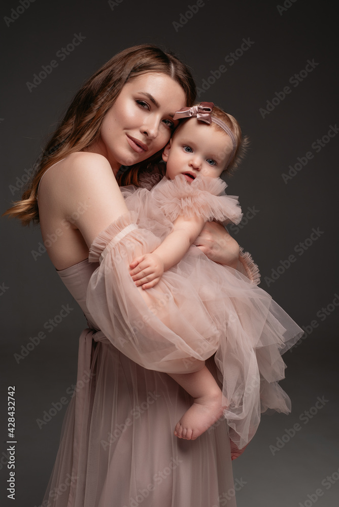 Woman in light clothes have fun with cute child baby girl. Mother, little kid daughter isolated on grey background, studio portrait. Mother's Day love family, parenthood childhood concept