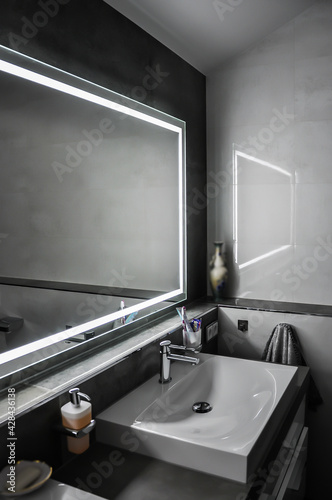 Detailaufnahme einer Waschtischanlage  mit ungew  hnlichen Fliesen. Weiterhin ist ein moderner Seifenspender und ein Ausschnitt eines beleuchteten Spiegels  zu sehen