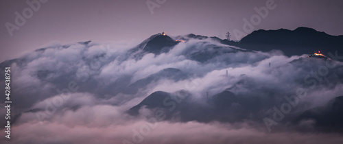 Photography Mesmerizing view of mountain peaks covered by clouds on background of the citysc