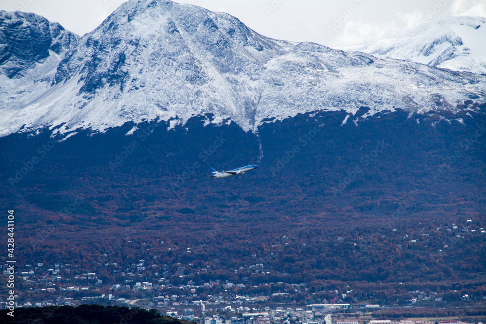 Plane taking off surrounded by snow mountains, Ushuaia.