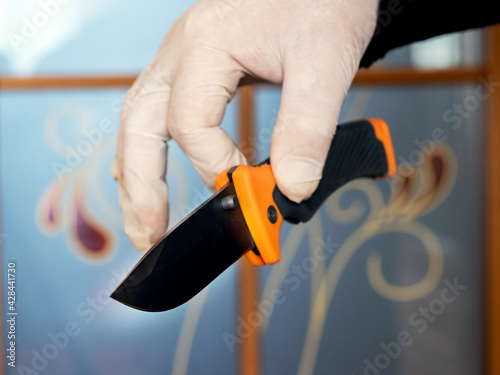 A gloved man carefully holds a knife as evidence of a crime. Knife in the hand of an expert, forensic scientist