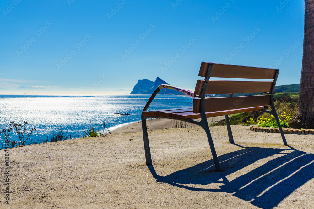 Bench on seashore and Gibraltar rock on horizon Bench on seashore and Gibraltar rock on horizon