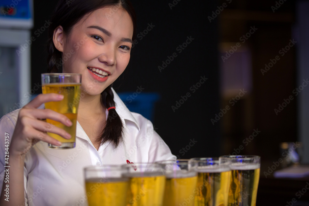 Beautiful Asian woman holding a glass of beer close up on background inside bar. Beautiful Asian woman holding a glass of beer close up on background inside bar.