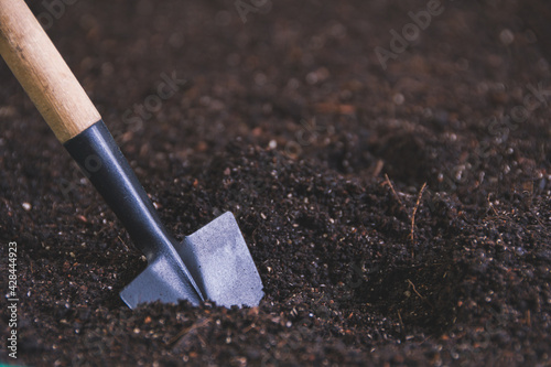 Small shovel in ground for planting seedlings. Gardening, tools for plant care. Spring work on garden