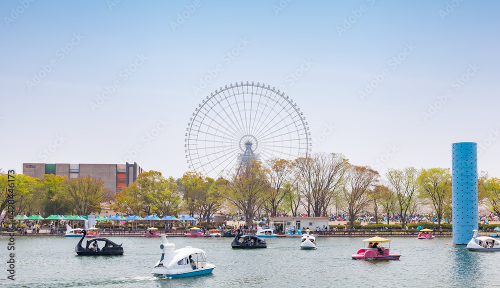 Fototapeta premium Pedal boats in Yume-no-ike (Dream Pond) and Expo '70 Pavilion in Expo '70 Commemorative Park, and Redhorse Osaka Wheel in Expocity in Osaka, Japan