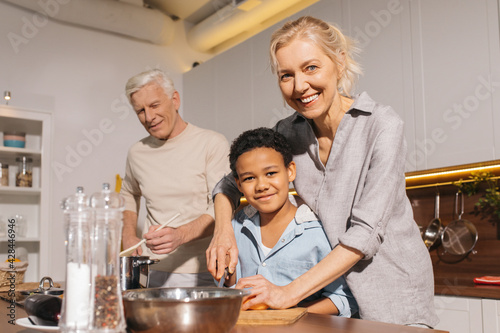 Happy multiracial family standing at the table while cooking at the kitchen