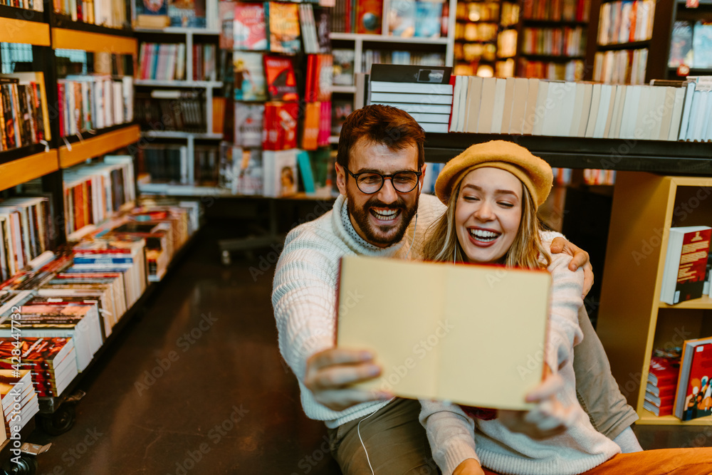 Young student couple in book store is showing plain paper. Young student couple in book store is showing plain paper.