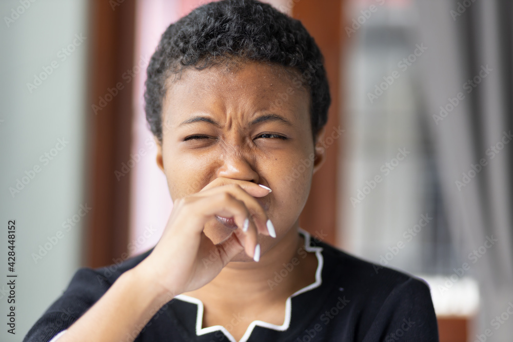 African woman having runny nose or covering her nose for bad smell, concept of stink thing, bad breath, unpleasant smell, odor, bad smell, young adult black African woman model African woman having runny nose or covering her nose for bad smell, concept of stink thing, bad breath, unpleasant smell, odor, bad smell, young adult black African woman model
