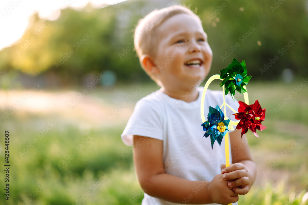 Smiling child with toy in summer park on sunny day. Cute little boy enjoying fresh spring weather. Childhood moment. Smiling child with toy in summer park on sunny day. Cute little boy enjoying fresh spring weather. Childhood moment.