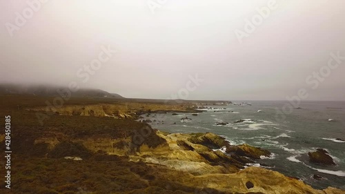 wide shot of a rocky coast line as ocean waves crash into rock structures
