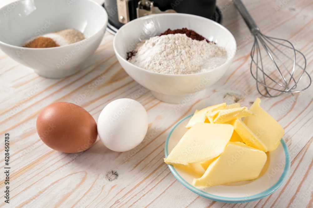Butter, eggs, flour and sugar, ingredients to bake a cake on a wooden table, selected focus