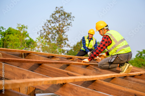 Two carpenters are working at the construction site. Construction of the wooden roof structure. Ideas for renovating and extending wooden houses.