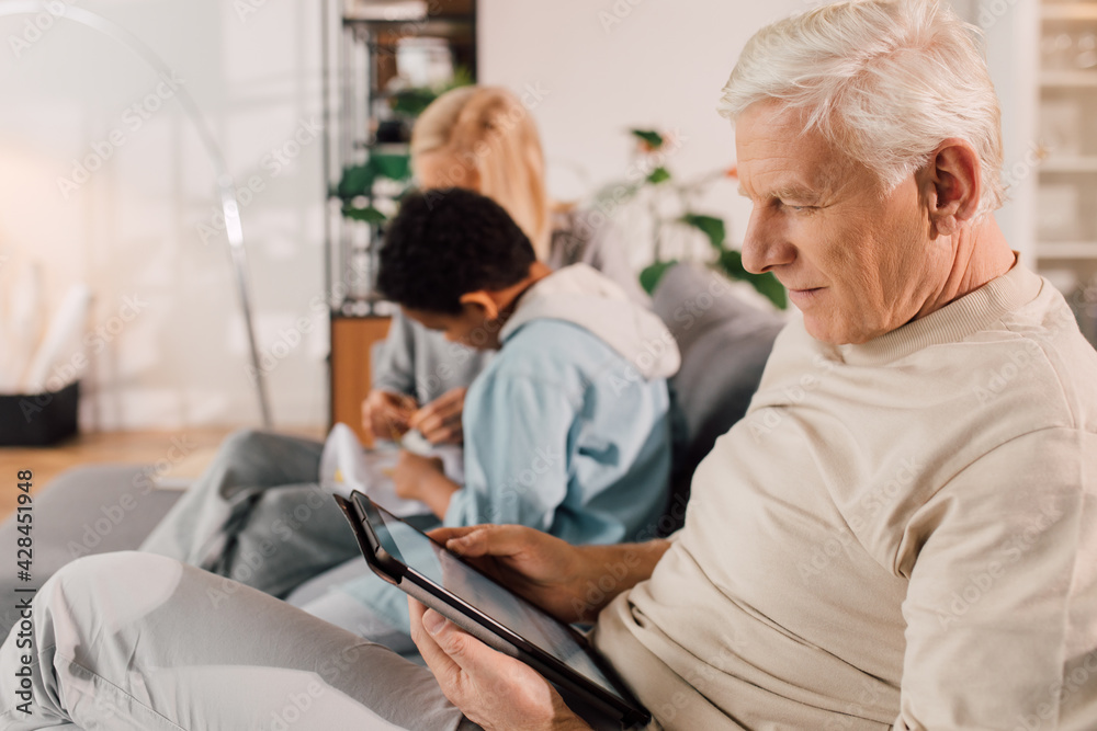 © Yakobchuk Olena - Boy asking his grandmother while she doing needlework at home
