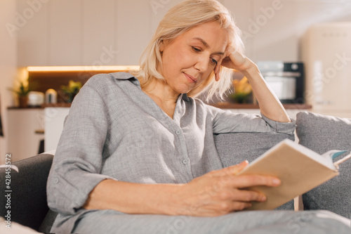 Woman sitting at the sofa and reading a book