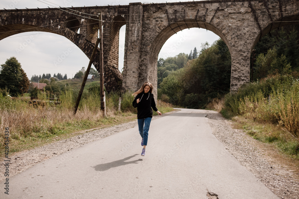 Young woman walking near old viaduct. Tourist girl in scenery countryside by the Historical abandoned railway arch bridge viaduct in Vorokhta, Ivano-Frankivsk Region, Ukraine