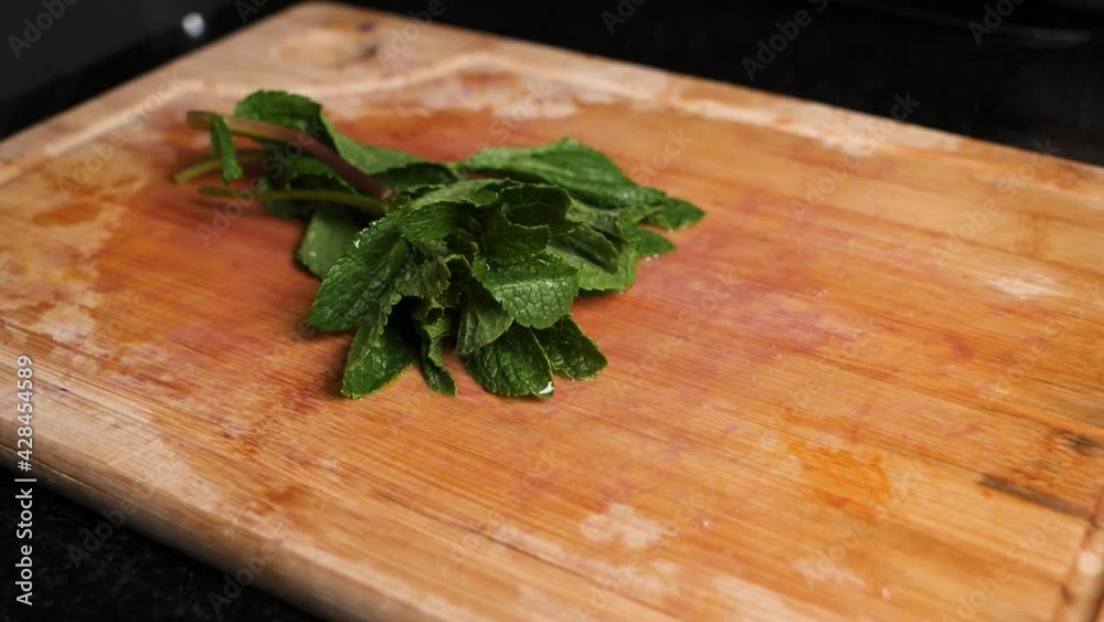 Dropping fresh juicy peppermint leaves on a wooden chopping board, slow motion. Dropping fresh juicy peppermint leaves on a wooden chopping board, slow motion.