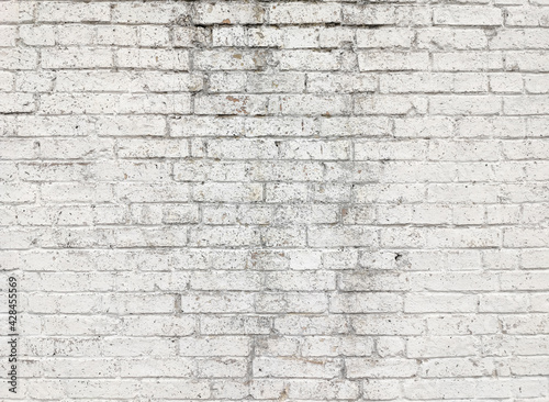 The texture of the old brick wall painted in white. Vintage brick background with cracked paint.