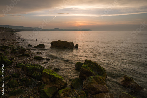 Golden hour sunset at Colwyn bay, North Wales. Warm sky and gentle waves along a rocky coastline