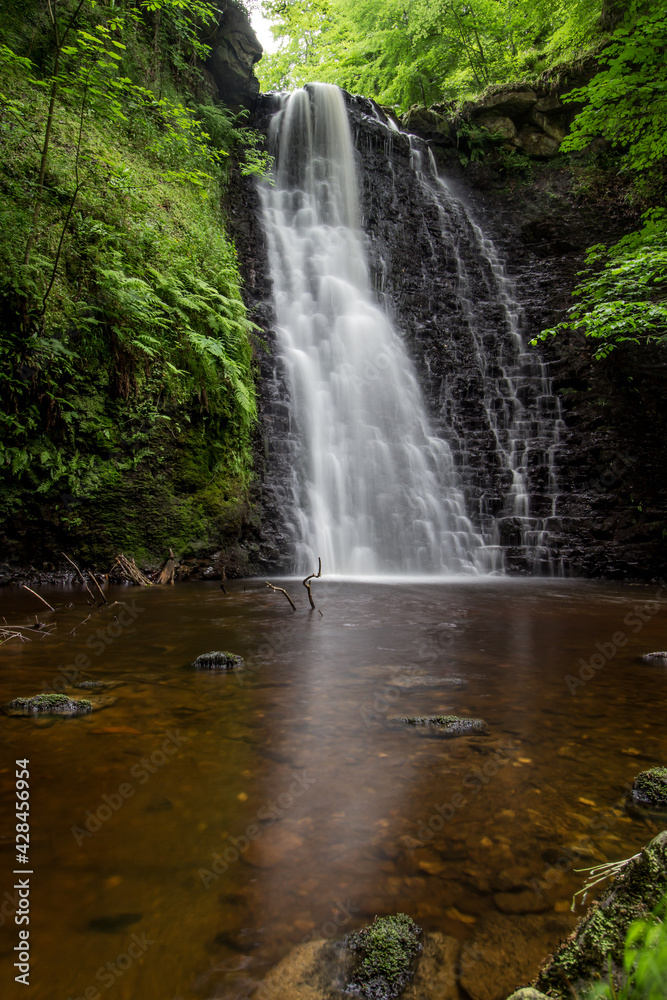 Large cascading waterfall tumbling into a peaceful pool. Falling foss waterfall, Yorkshire Dales 