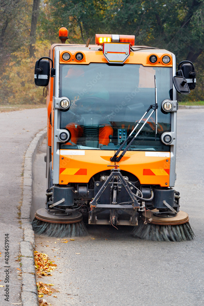 A municipal street sweeper car is sweeping the carriageway of a city road.