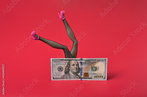 Sexy woman legs in black fishnet stockings over dollar bill. Sex for money concept. Red background, copy space. photo