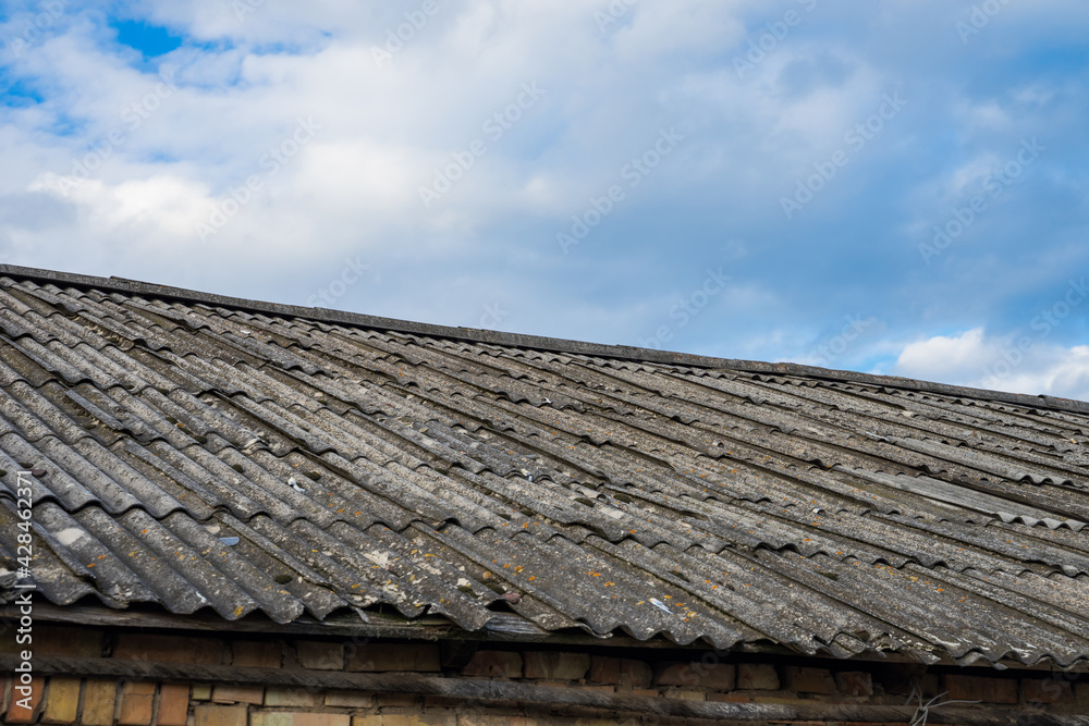 Old asbestos roof slates against blue sky Old asbestos roof slates against blue sky