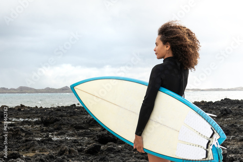 Konstfotografi Multiracial surfer young woman standing by the sea