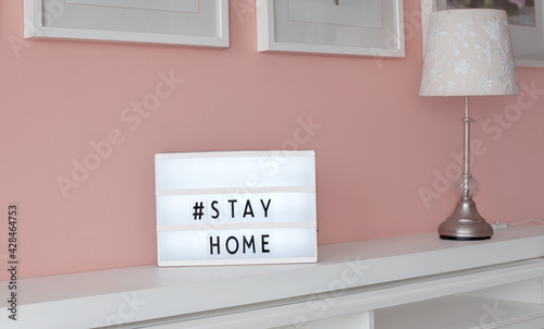 Stay home prevention message on white sign at home on a green shelf. Coronavirus text, people staying home for social distancing. photo