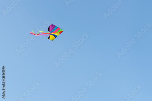 Flying kite in cloudless blue sky.