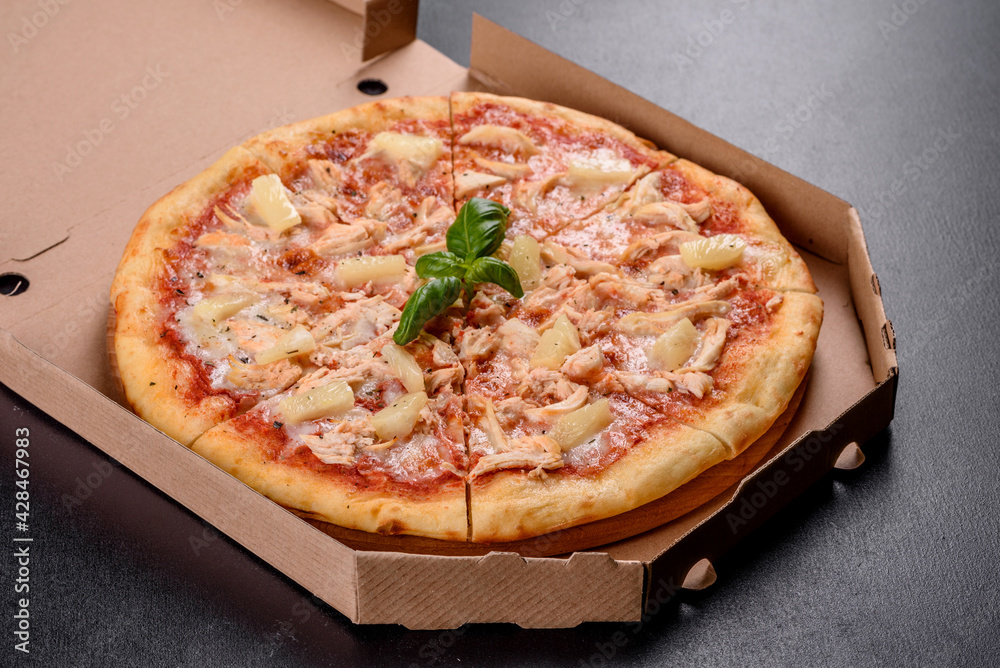 Tasty fresh oven pizza with tomatoes, cheese and pineapple on a dark concrete background