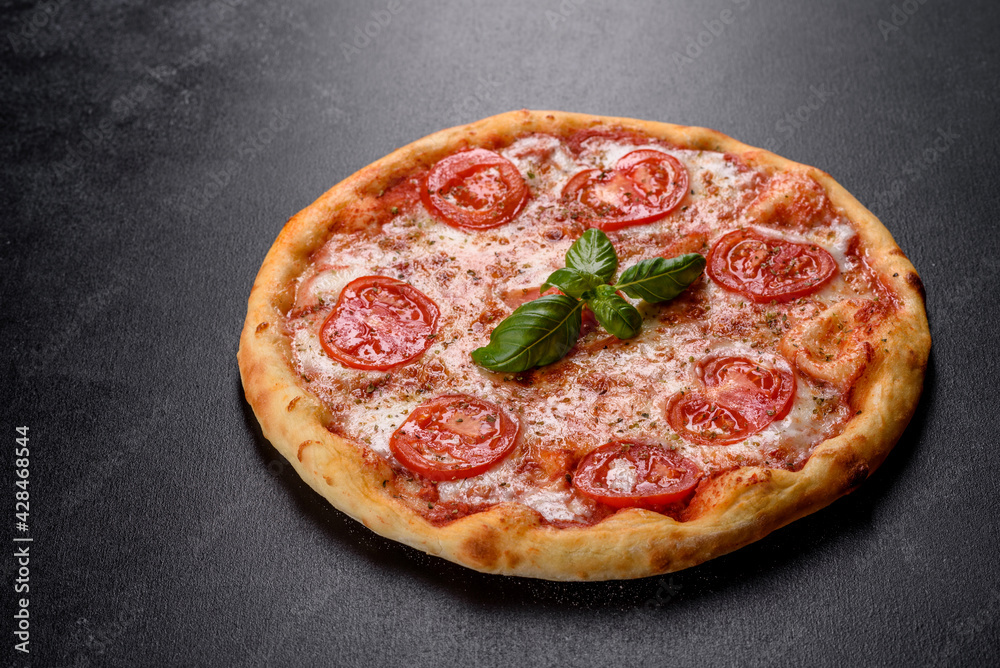 Tasty fresh oven pizza with tomatoes, cheese and basil on a concrete background
