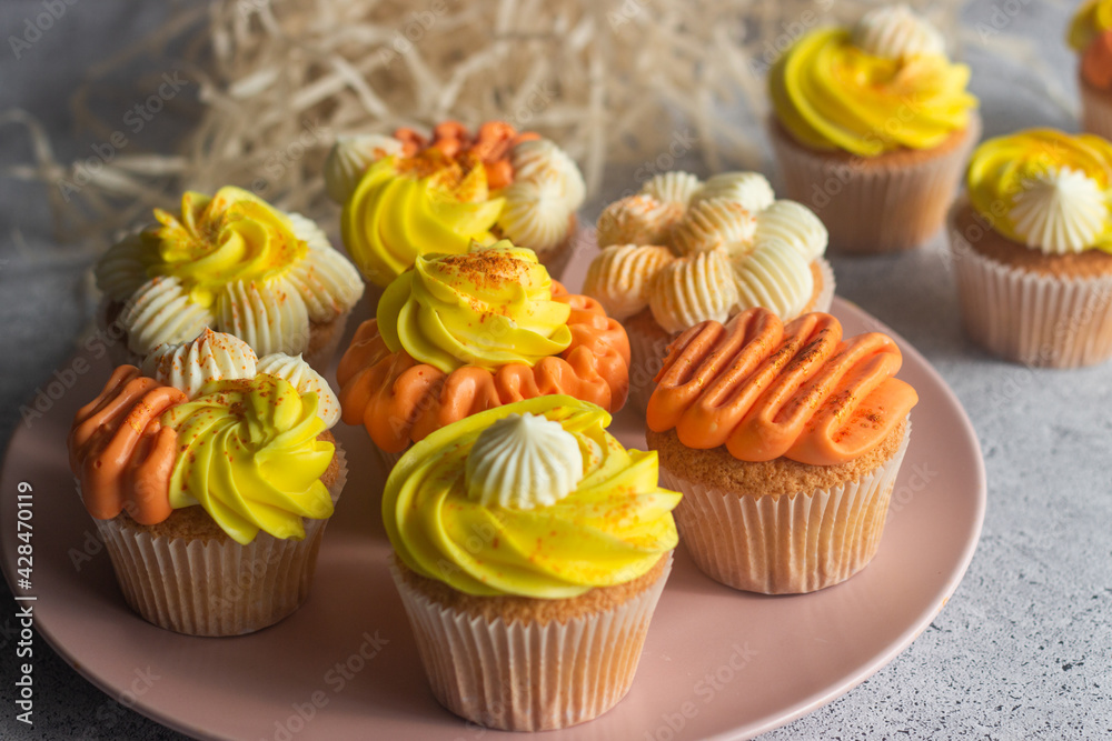 Delicious muffins. Orange and lemon cream muffins. Cupcakes on a concrete table 