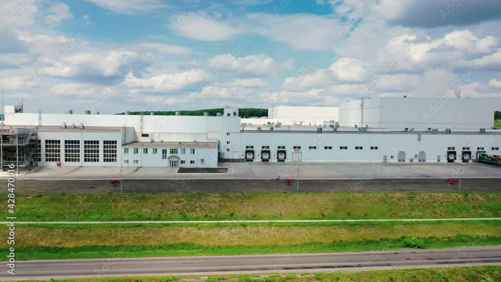 Industrial complex under blue sky. Innovative manufacturing near the road. Industry in nature. Motion camera to the right. Industrial complex under blue sky. Innovative manufacturing near the road. Industry in nature. Motion camera to the right.