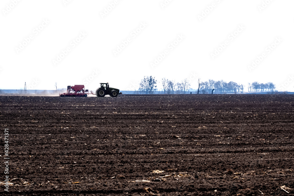 Fototapeta premium tractor with seeder in the field in early spring