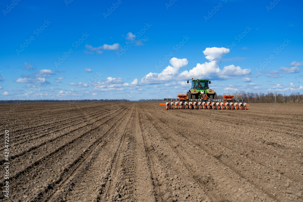 Fototapeta premium tractor with seeder in the field in early spring