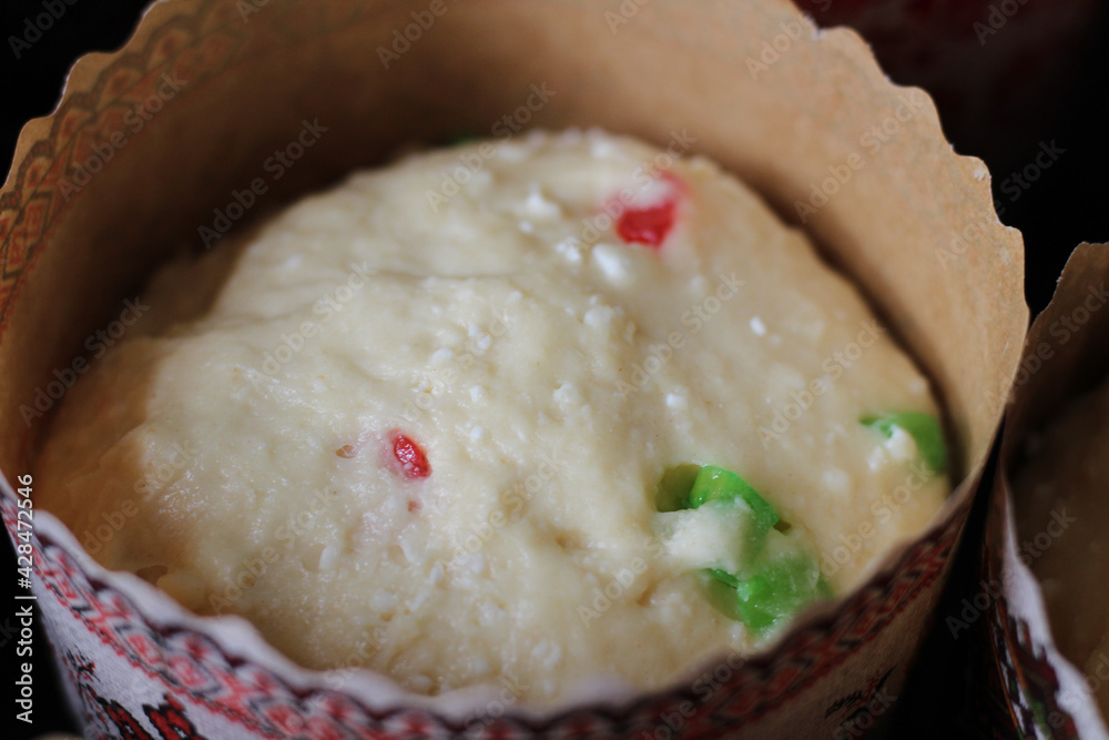 Raw dough with candied fruits for Easter cakes in paper tins, ready for baking Raw dough with candied fruits for Easter cakes in paper tins, ready for baking