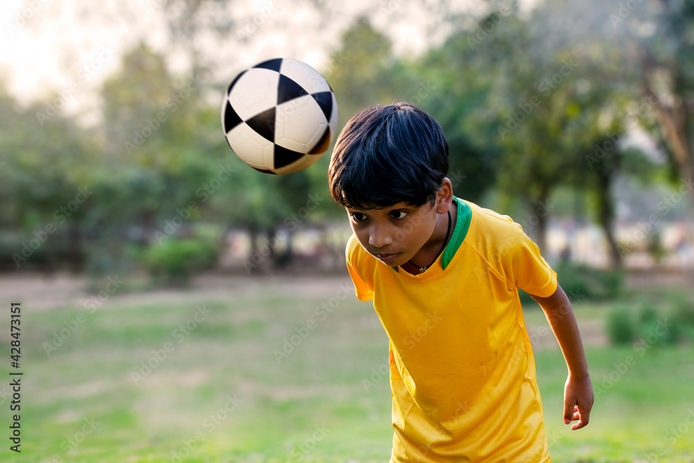 Portrait of boy heading football	