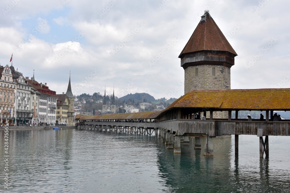Lucerne, Switzerland - 04 17 2021: Chapel Bridge over river Reuss with Water Tower built in water in Lucerne in Switzerland. A historical building and a landmark of the city attracting tourists. 