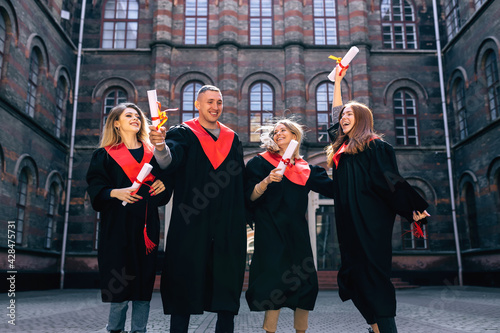 cheerful  contented  students  jumping rejoicing at the end of their studies  holding their hands up with a document.