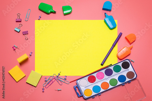 Stationery items on the pink background with free space for text. Creative, colorful background with scool supplies. Flatlay with copy space, top view. Markers, paper clips, sticky notes photo
