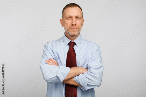 Middle aged bearded serious businessman posing on white background