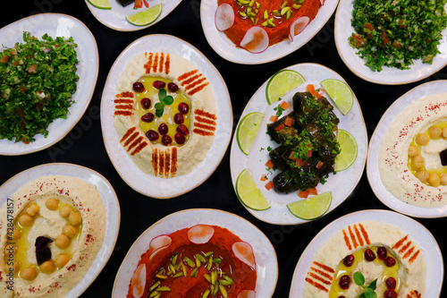 selection of libanese food mezze, includes hummus, muhammara, moutabal, taboule and vine leaves
