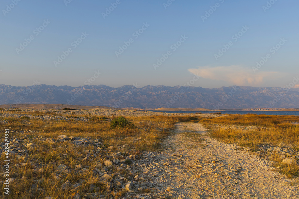 View to Velebit mountains across rocky island road at sunset, Adriatic sea, Dalmatia, Croatia