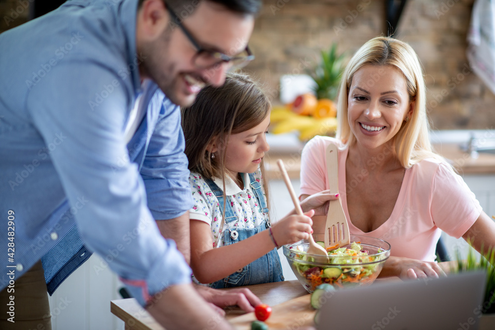 Family using laptop during cooking in kitchen Family using laptop during cooking in kitchen